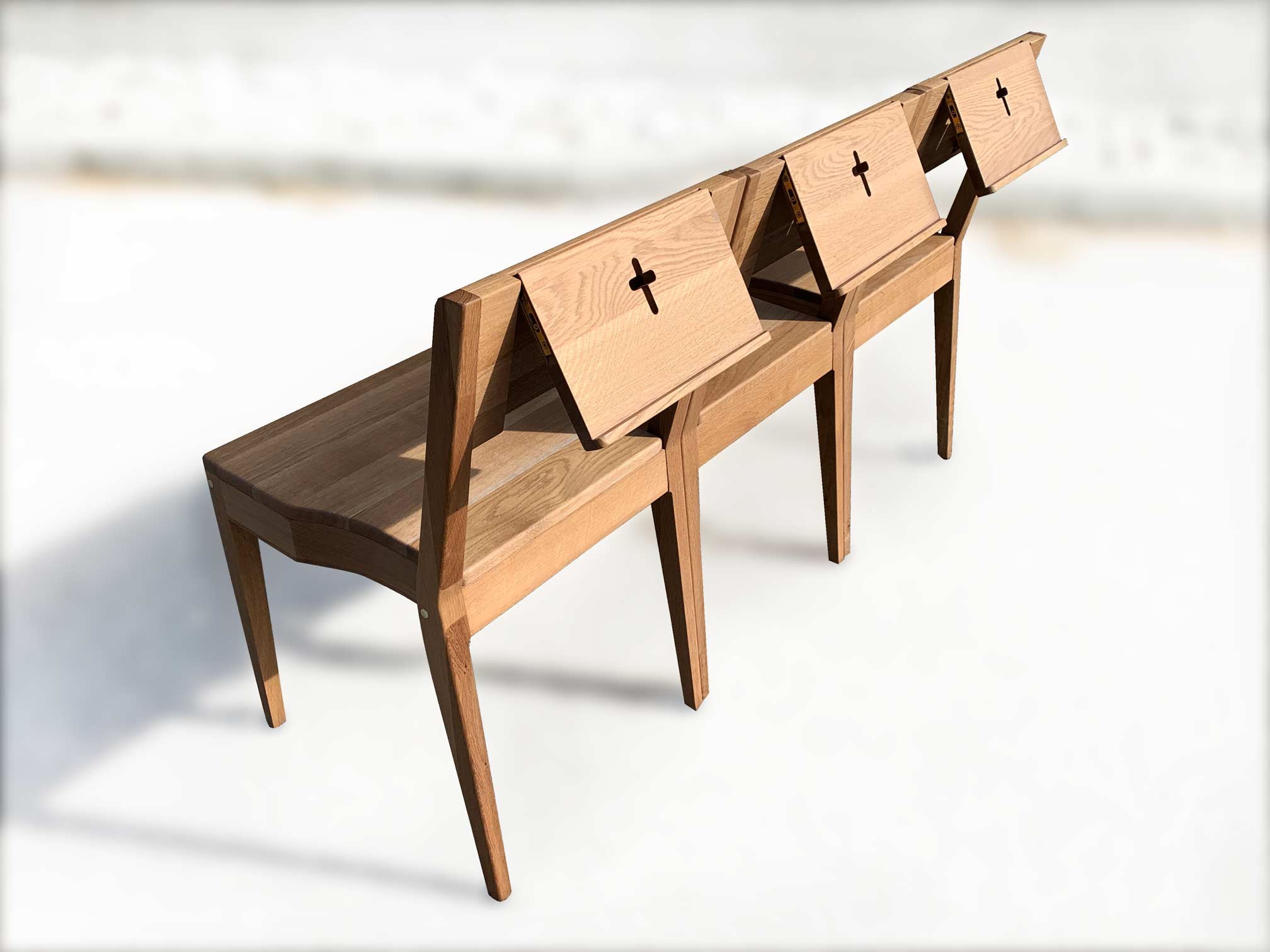 Three church chairs in pew with Bible holders made of oak wood.
